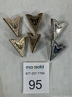 Front view of six ornate collar tips showing engraving and finish