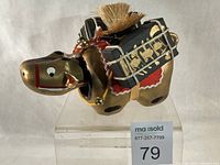 Front left view of gold Akabeko showing red blanket and black saddle packs