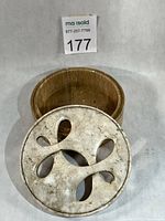 Lid removed showing pierced design and interior of tan soapstone base