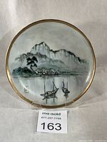 Front view of porcelain plate with landscape scene and gold rim