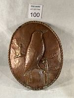Front view of oval copper plaque showing bird motif and twisted border