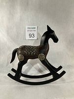 Profile view of wood and metal rocking horse showing saddle and brass accents