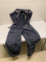 Full view of Helly Hansen bib pants laid flat showing suspenders and leg design