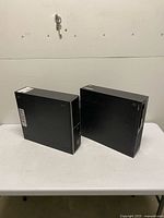 Both desktop towers standing on table showing front and side panels