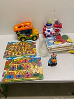 Group shot showing dump truck, activity train, stack of puzzle boards, two train-themed peg puzzles and ceramic unicorn