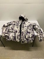 Front view of Remington snow camouflage jacket displayed on table