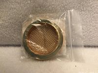 Front view of one gold screened sound hole cover in sealed bag