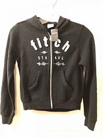 Front view of black zip-up hoodie with graphic and pockets