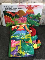 Retail box front showing Hahaland Baby First Cloth Books Dinosaur Tails and unopened book