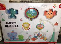Front of sealed box showing Happy Bed Bell mobile, cut-out windows display elephant, projector disc, fish rattle