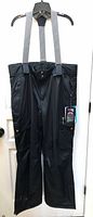 Front view of black Firefly insulated snow pants with suspenders and hangtag