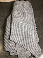 Folded grey ribbed knit scarf showing texture