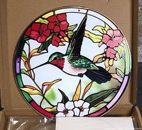 Front view of circular hummingbird plexiglass suncatcher in box