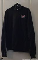 Front view of black hoodie hanging, butterfly patch visible