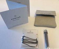 Entire set laid out: pendant, chain, pouch, instruction booklet