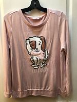 Full view of pink long-sleeve pajama top on hanger
