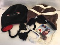 Black pirate skull hat and brown football hat, front view with tags