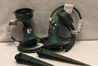 two green floodlight holders with stakes and cords