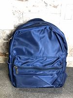 Front view of navy nylon mini backpack showing front zip pocket and overall design
