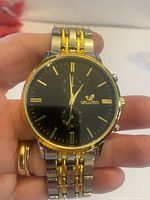 Front view showing black dial, gold indices, Orlando logo