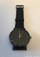 Front view of black dial watch with gold markers and hands