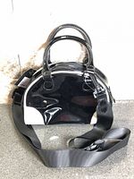front view of glossy black and white mini satchel with shoulder strap