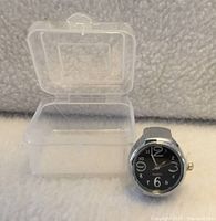 ring watch front view beside open plastic box