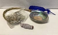 All kit items laid out: abalone shell, blue feather, sweetgrass, bag of sage, smudge stick