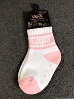 Front view of packaged Vans baby socks showing size 12-24M, white with pink details and grip dots