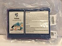 Front of sealed Yiclick African Exfoliating Net package displaying brand and usage information, blue and purple cloth edges visible
