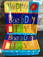 Front view showing multicolour Happy Birthday square plates in sealed packs