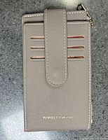 Front view showing strap closure, four card slots, gold imprint