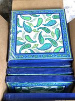 Open box showing multiple sealed packs of paisley napkins