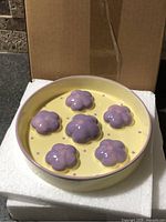 Top view of ceramic slow feeder bowl showing six purple flower obstacles on yellow base