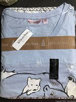 Folded pajama set with tags and ribbon showing brand tag and material label