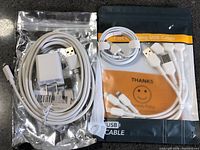 Foil bag with cable and wall charger beside retail pouch with additional cables
