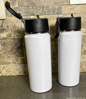 Two white stainless steel water bottles standing upright