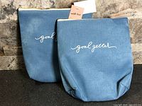 Two blue pouches standing side by side showing exterior design and tags