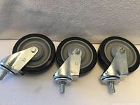 Front view of all three 5" swivel casters showing rubber tread, hubs, and stem mounts