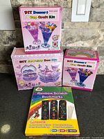 Group shot showing two Dessert Cup Craft Kit boxes, Jewelry Box Kit box, and Rainbow Scratch Bookmarks set