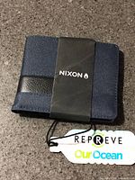 Folded wallet with Nixon band and Repreve Our Ocean hang tag