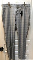 Full view of grey plaid dress pants hanging