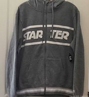 Front view of grey Starter full-zip hoodie showing logo, pockets, drawstrings