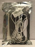 Front view of sealed foil package showing eye mask and coiled USB cable with controller