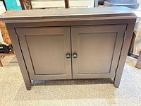 Front view of dark brown two-door cabinet with wood knobs