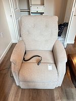 Front view of beige power recliner with remote on seat