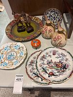 Group shot of charger, four small plates, two jugs, two figurines