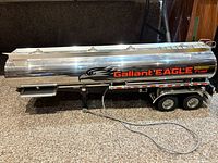 Left side view of chrome tanker trailer showing Gallant EAGLE Fuel decals, tandem axles and hose