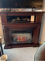 Front view of Dimplex corner fireplace showing mantel, media shelf, and lit firebox