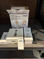 Lot overview showing VTech phone box, Liftware boxes, remote outlet package, magnifying glass